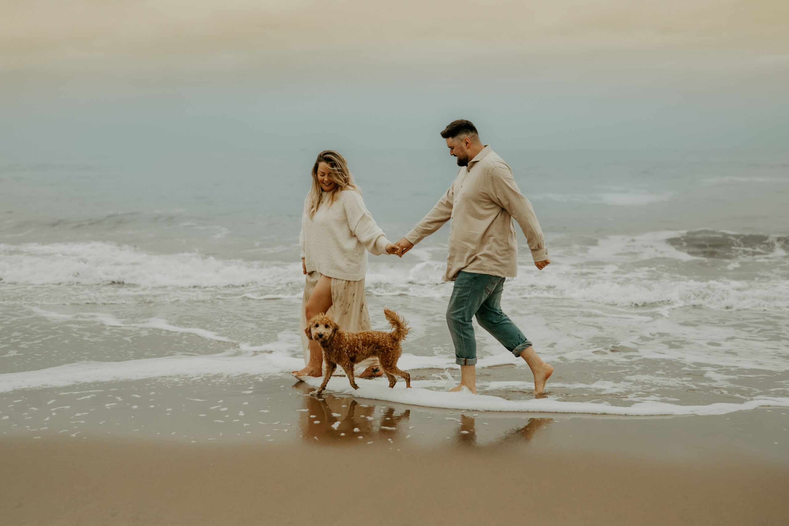 Hund mit Mann und Frau am Meer, gemeinsamer Moment in entspannter Atmosphäre